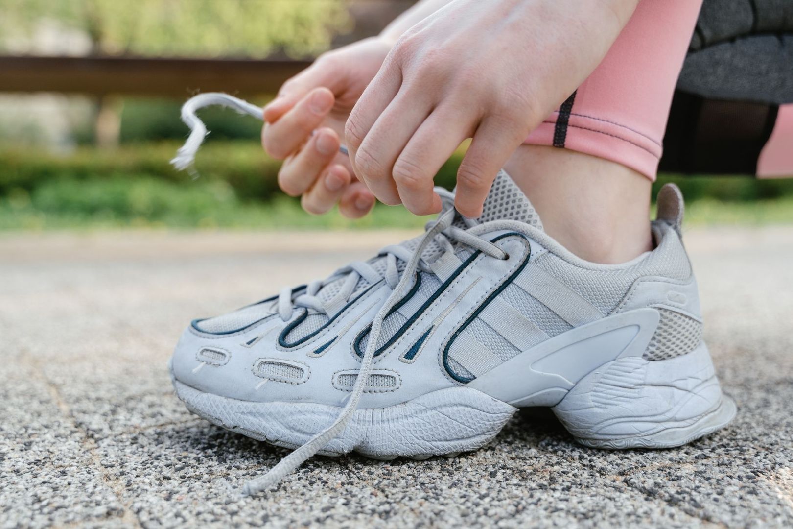 Runner tying the laces of a gray athletic shoe outdoors