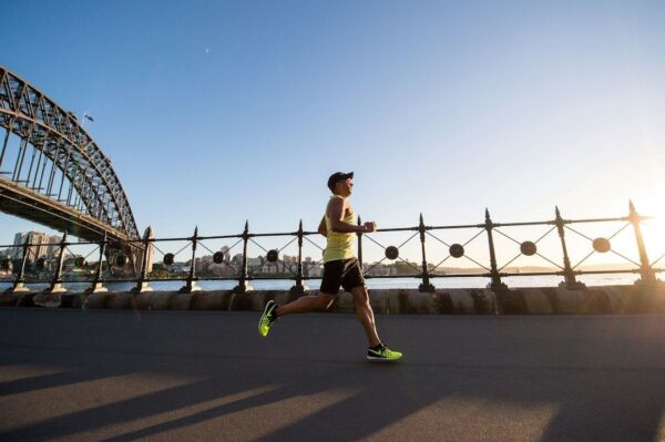 Runner maintains pace along a waterfront bridge at sunrise